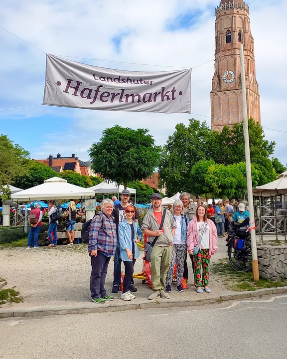 Menschengruppe am Haferlmarkt mit großem Transparent der Veranstaltung und Kirche im Hindergrund