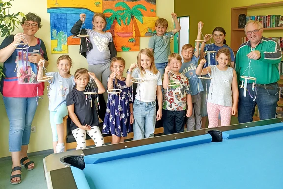 Kinder und Erwachsene präsentieren ihre gebastelten Windspiele