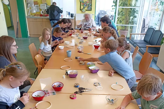 Kinder und Erwachsene basteln an einem langen Tisch andere Perspektive