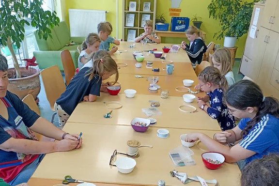 Kinder und Erwachsene basteln an einem langen Tisch